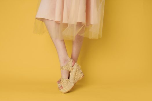 Woman in dress legs shoes attractive look yellow background fashion. High quality photo
