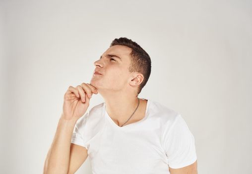 Portrait of a pensive man in a white T-shirt side view light background. High quality photo
