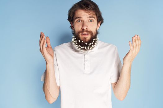 Cheerful car white T-shirt flowers in a beard close-up blue background. High quality photo