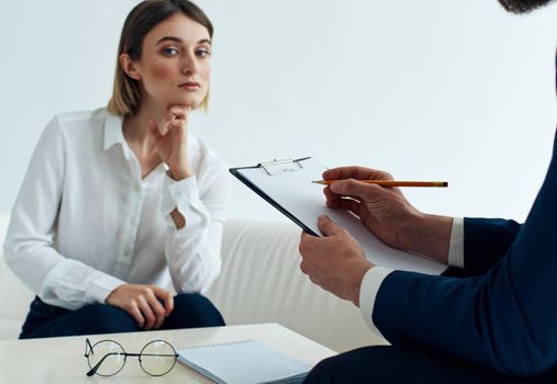 A man with documents and a woman on the couch at the table indoors staff psychologist reception doctor. High quality photo