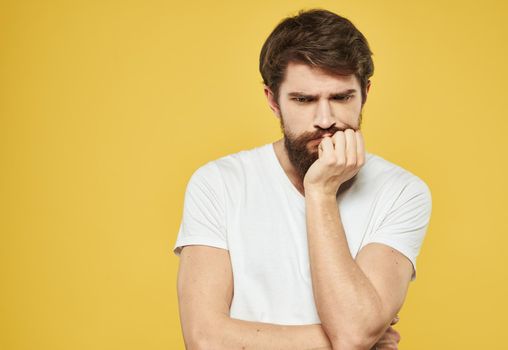 A man touches his face with his hands puzzled look yellow background cropped view. High quality photo