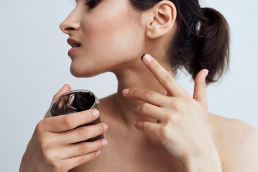 Pretty brunette naked shoulders black cream skin care close-up. High quality photo