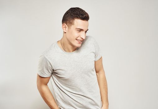 Cheerful handsome man in a white T-shirt gray background. High quality photo