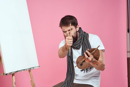 Male artist scarf around his neck paints drawing art pink background. High quality photo
