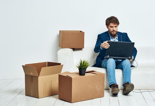 Manager sits on the couch with a laptop working professional boxes with things. High quality photo
