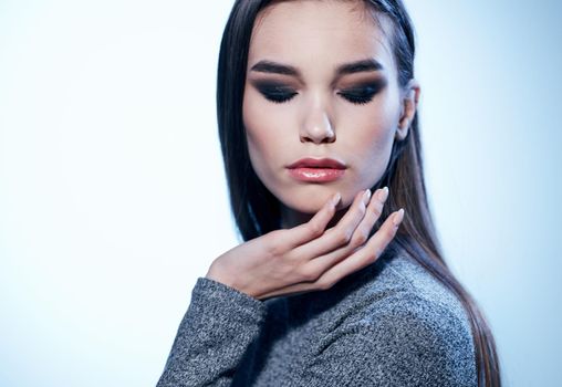 Elegant woman in a gray sweater on a light background Makeup on the face. High quality photo