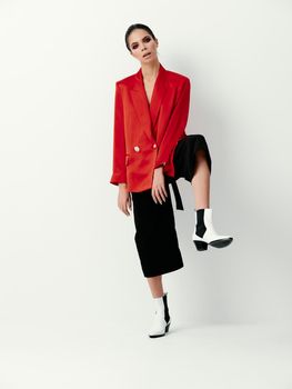 pretty brunette red jacket leg bent at the knee isolated background posing. High quality photo