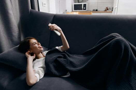 happy woman with a mobile phone in front of her eyes lies on a comfortable soft sofa. High quality photo