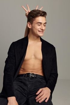 Cheerful man with an unbuttoned shirt sits on a luxury romance studio chair. High quality photo