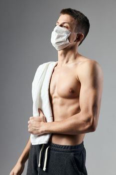 sporty man in medical mask towel on shoulders pumped up body cropped view lifestyle. High quality photo