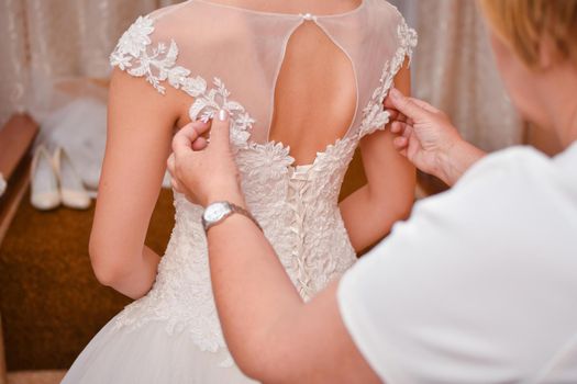 The bride is being prepared for marriage. Mom dresses her daughter bride. Photo from the back.