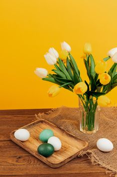 easter eggs bouquet flowers holiday yellow background. High quality photo