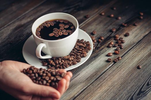 saucer with coffee beans and white cup on a wooden table side view Copy Space. High quality photo