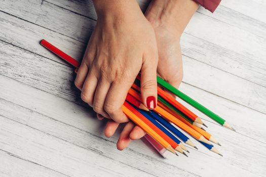 colored pencils female hands top view wooden table office. High quality photo