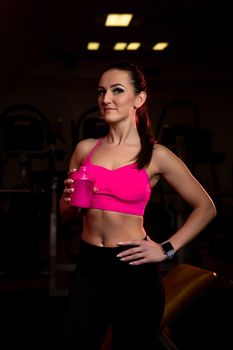 fitness woman drinks from a sports bottle in the gym.