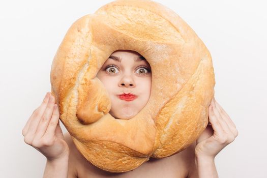 energetic woman grimaces and holds a round loaf of bread in front of her face. High quality photo