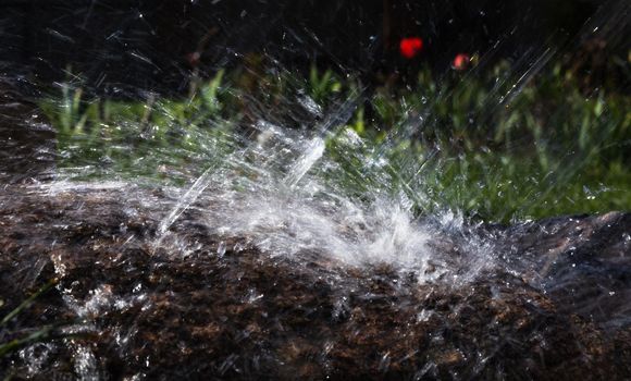 Wet stone in the rain. Rain water drop falling to the stone. Water is flowing and splashing around them.