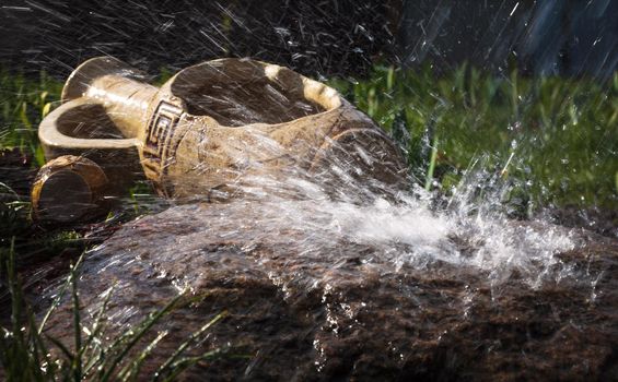 Wet stone and decorative antique urn in the rain. Rain water drop falling to the stone. Water is flowing and splashing around them.