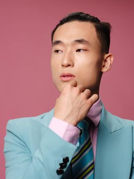 Man asian appearance close-up blue suit pink background emotions. High quality photo