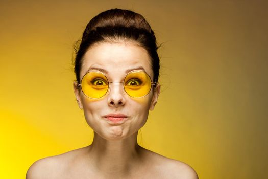 cheerful brunette naked shoulders yellow glasses emotions studio. High quality photo