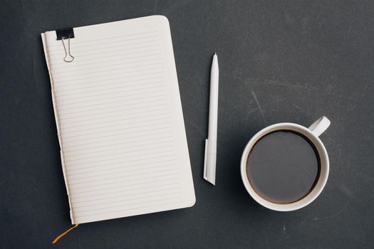 notebook with pen on dark background and cup of coffee office top view. High quality photo