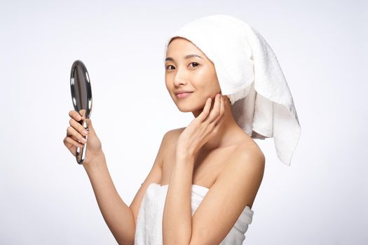 woman with a towel on her head holding a mirror in her hands skin care lifestyle. High quality photo