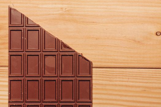 brown chocolate bar cut diagonally on wooden background. High quality photo
