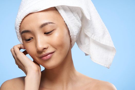 pretty cheerful woman of asian appearance with a towel on her head close-up blue background. High quality photo