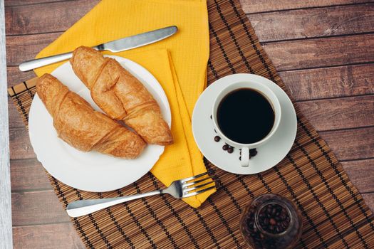 fresh croissants on a saucer table setting breakfast cup with drinks. High quality photo