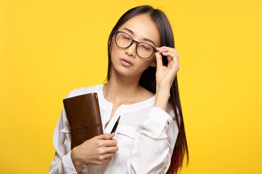 Business woman in glasses holding notepad in hands official yellow isolated background. High quality photo
