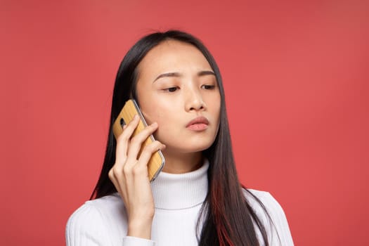 woman of asian appearance talking on the phone technology emotions red background. High quality photo