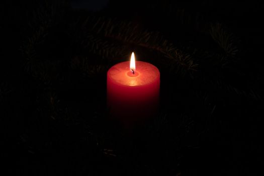 Christmas motif with red burning candle and black background