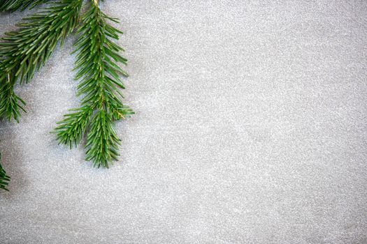 Christmas motif, texture, background with branches of a Nordmann fir left at the top on a grey marbled  background with free space for text