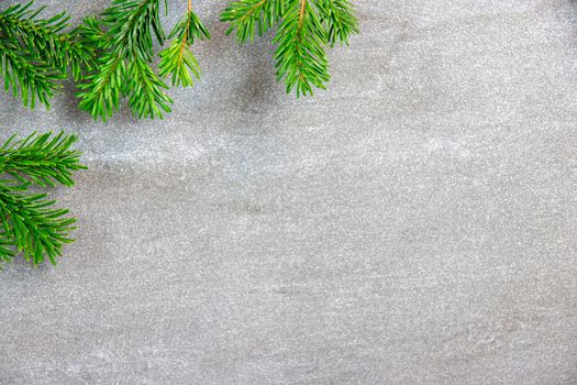 Christmas motif, texture, background with branches of a Nordmann fir left at the top on a grey marbled  background with free space for text