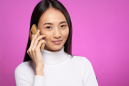 woman of asian appearance talking on the phone technology lifestyle pink background. High quality photo