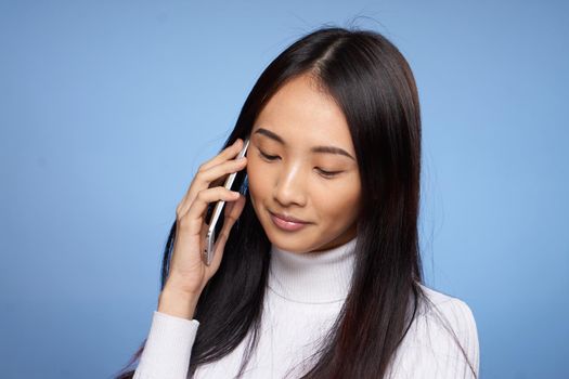 woman of asian appearance talking on the phone technology blue background. High quality photo