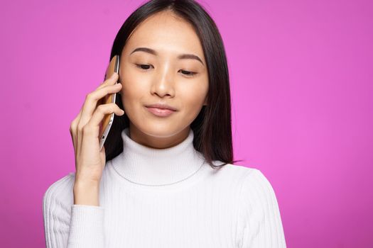 woman of asian appearance talking on the phone technology lifestyle pink background. High quality photo