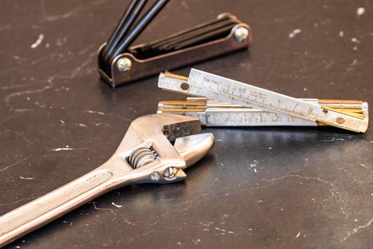 Tools for repair and building. Adjustable spanner, ruler and instruments on black wooden table with copy space