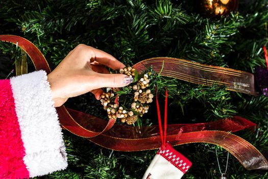 Decorating Christmas tree, hand putting Christmas decorations on fir branches. Christmas hanging decorations.