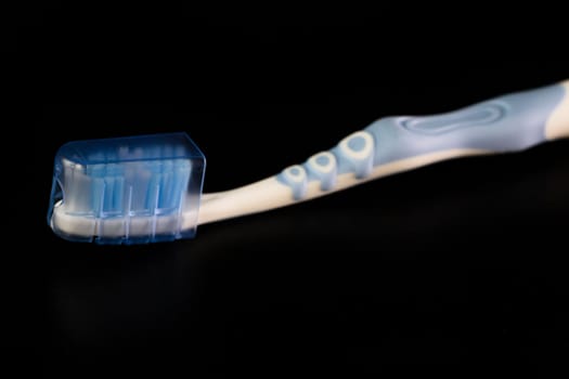 Selective focus on toothbrush isolated on black background.