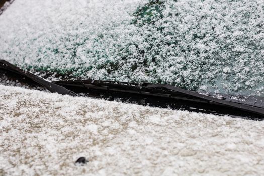 Snow on car, windshield wipers with snow close up.