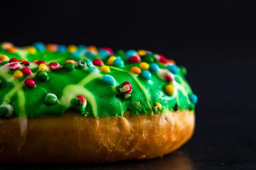 Green glazed donut with sprinkles isolated. Close up of colorful donut.