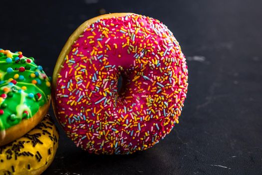 Glazed donuts with sprinkles isolated. Close up of colorful donuts.