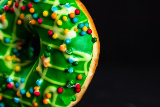 Green glazed donut with sprinkles isolated. Close up of colorful donut.