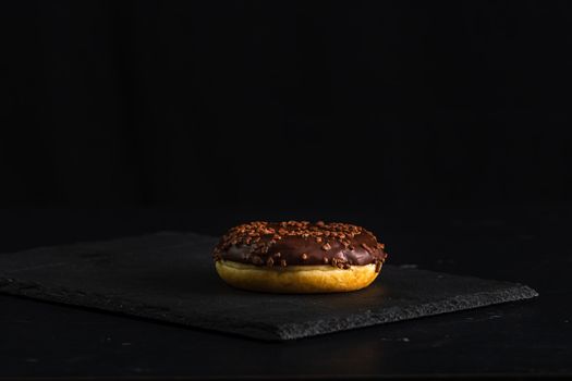 Chocolate glazed donut with chocolate chips isolated. Close up of delicious donut.