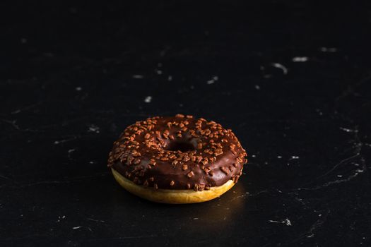 Chocolate glazed donut with chocolate chips isolated. Close up of delicious donut.