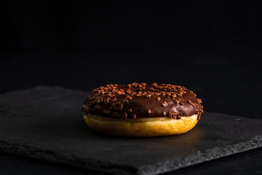 Chocolate glazed donut with chocolate chips isolated. Close up of delicious donut.