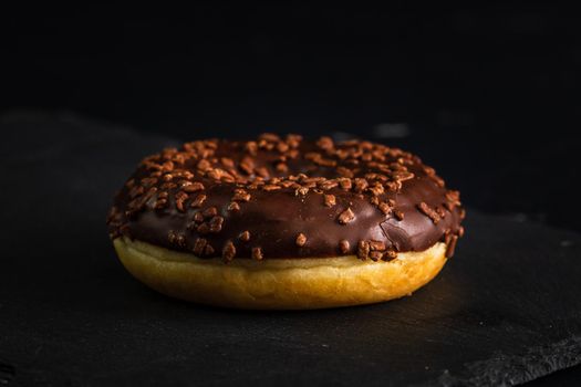 Chocolate glazed donut with chocolate chips isolated. Close up of delicious donut.