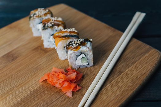 sushi rolls red ginger chopsticks wood board close-up. High quality photo
