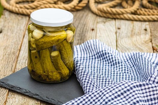 Close up of glass jar with pickles isolated. Preserved food concept, canned vegetables isolated in a rustic composition.